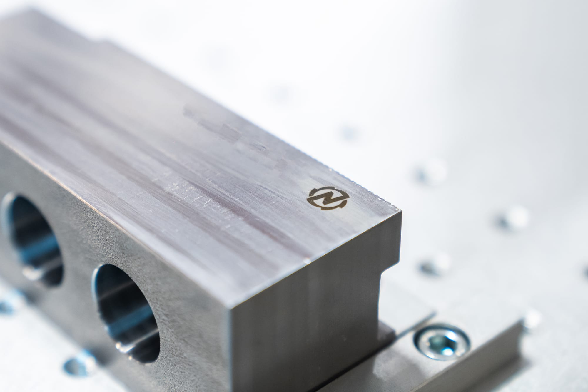 Detail van een gefreesd aluminium onderdeel met het ingegraveerde merkteken van Fijn Mekaniek Nelissen